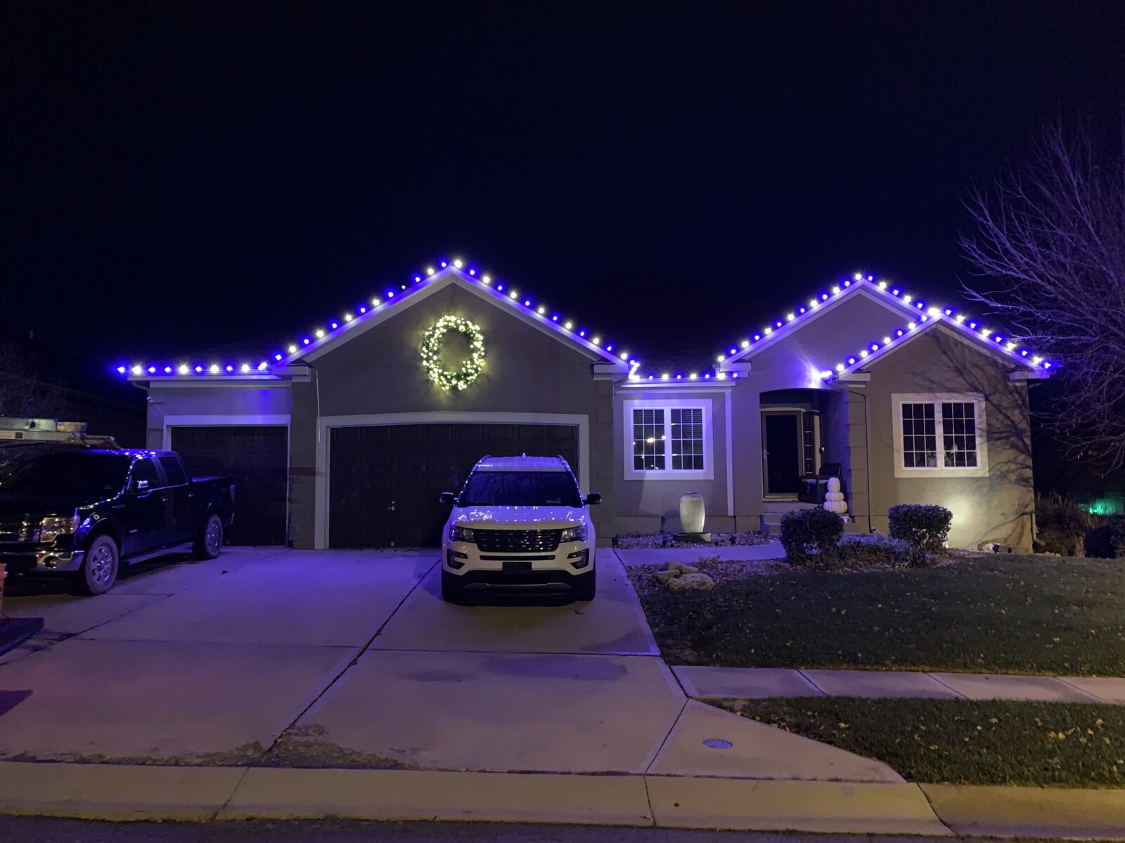 Blue and purple C9 lights with lit wreath on ranch home
